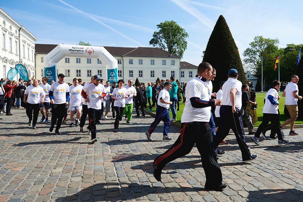 Die Läuferinnen und Läufer starten den Fackellauf der Special Olympics im Ehrenhof von Schloss Bellevue 