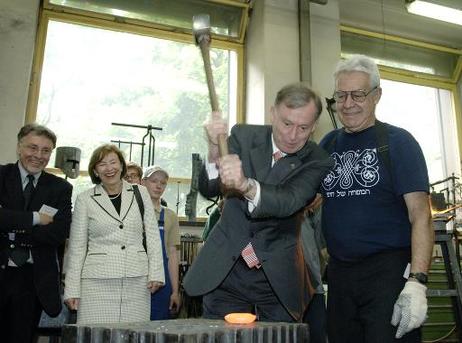 Bundespräsident Horst Köhler am Amboß in der Schmiede der Initiative. Junge und alte Metallhandwerker sammeln gespendete Werkzeuge und Maschienen und reparieren diese. Damit wird ein Container mit komplett eingerichteter Schlosserwerkstatt für das Sozialp