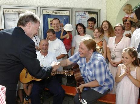 Bundespräsident Horst Köhler wird von einer jungen Frau (mit Gitarre) am katholischen Gemeindezentrum begrüßt.
