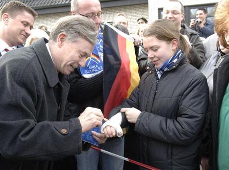 Bundespräsident Horst Köhler gibt einem jungen Mädchen ein Autogramm auf ihren eingegipsten Arm.