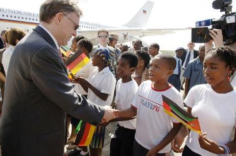 Bundespräsident Horst Köhler wird von Kindern (mit Fähnchen) auf dem Flughafen von Beira begrüßt.