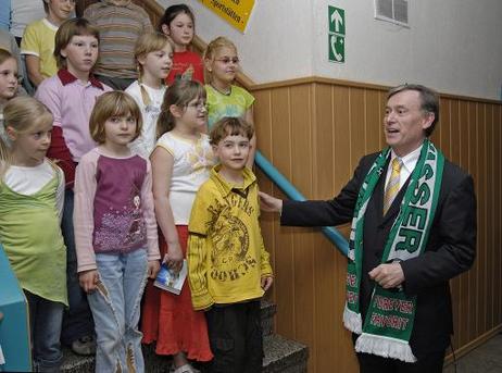 Bundespräsident Horst Köhler (mit Fan-Schal) mit Kindern des Chores der Kita 'Regenbogen' im Turnerheim des SV Grün-Weiß.