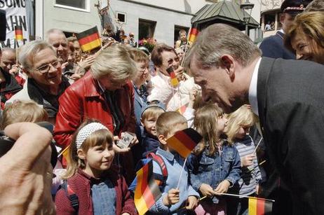 Bundespräsident Horst Köhler unterhält sich mit einem kleinen Mädchen (mit Fähnchen).