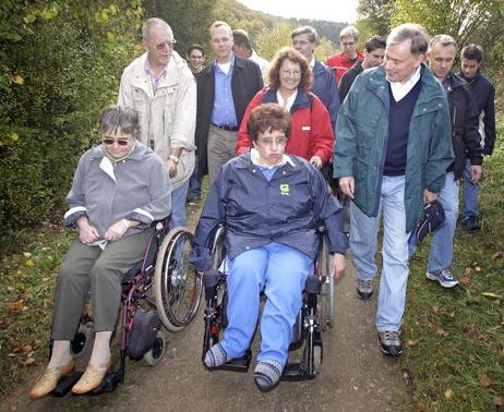 Bundespräsident Horst Köhler (r.) spricht mit Frauen im Rollstuhl während seiner Wanderung durch die Eifel. Er besichtigt als Schirmherr des 'Jahres der Naturparke 2006' den barreirefreien Wanderweg im Deutsch-Belgischen Naturpark Hohes Venn-Eifel.