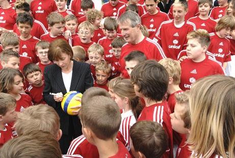 Eva Luise Köhler signiert einen Ball am Rande einer Scheckübergabe für UNICEF.