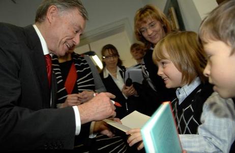 Bundespräsident Horst Köhler gibt Kindern ein Autogramm in ein Buch.