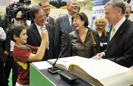 Bundespräsident Horst Köhler wird vor dem Gästebuch der Stadt Essen von einem Jungen fotografiert (l.: Armin Laschet, Minister für Generationen, Familie, Frauen und Integration Nordrhein-Westfalens; M.: Eva Luise Köhler).