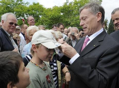 Bundespräsident Horst Köhler gibt einem Jungen ein Autogramm auf den Schirm der Mütze.