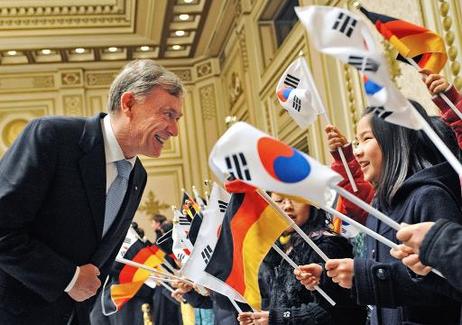 Bundespräsident Horst Köhler im Gespräch mit Schulkindern mit deutschen und koreanischen Fähnchen im Amtssitz des Präsidenten.