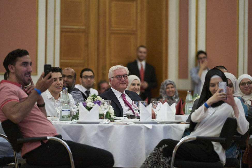 Bundespräsident Frank-Walter Steinmeier schaut dem Auftritt von Khalid Bounouar im Berliner Rathaus anlässlich des Iftar-Essens der Initiative JUMA zu
