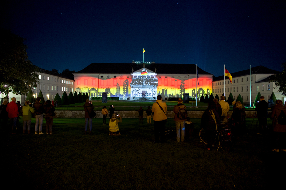Zuschauer schauen sich die Projektion auf der Schlossfassade bei der Eröffnung der Projektion zum Sonder-Award 'Demokratie' beim Festival of Lights 2017 in Schloss Bellevue an