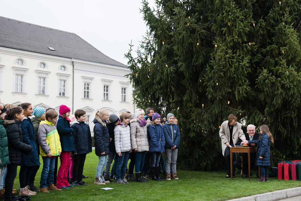 Bundespräsident Frank-Walter Steinmeier und Elke Büdenbender schalten die Beleuchtung des Weihnachtsbaums mit Hilfe von Schahd Halawa, Schülerin der Mühlenau-Grundschule aus Berlin-Dahlem, im Ehrenhof von Schloss Bellevue an