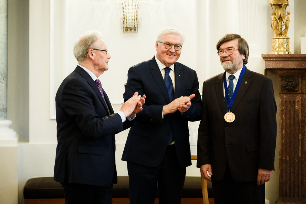 Bundespräsident Frank-Walter Steinmeier beglückwünscht Imre Kónya nach der Übergabe der Adalbert-Medaille zusammen mit Hans Süssmuth bei der Verleihung des Internationalen Adalbert-Preises im Langhanssaal von Schloss Bellevue 