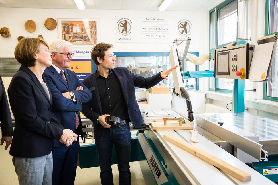 Bundespräsident Frank-Walter Steinmeier und Elke Büdenbender werden durch Sebastian Neuhaus, Leiter des Fachbereichs Tischler und Holztechniker, durch die Werkstatt im Bildungs- und Technologiezentrum im Rahmen der Woche der beruflichen Bildung geführt