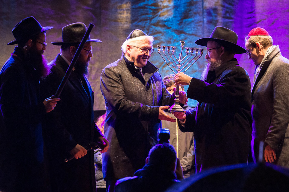 Bundespräsident Frank-Walter Steinmeier bekommt einen Chanukkaleuchter von Rabbiner Yehuda Teichtal bei den Feierlichkeiten zum Entzünden des Chanukkaleuchters am Brandenburger Tor überreicht