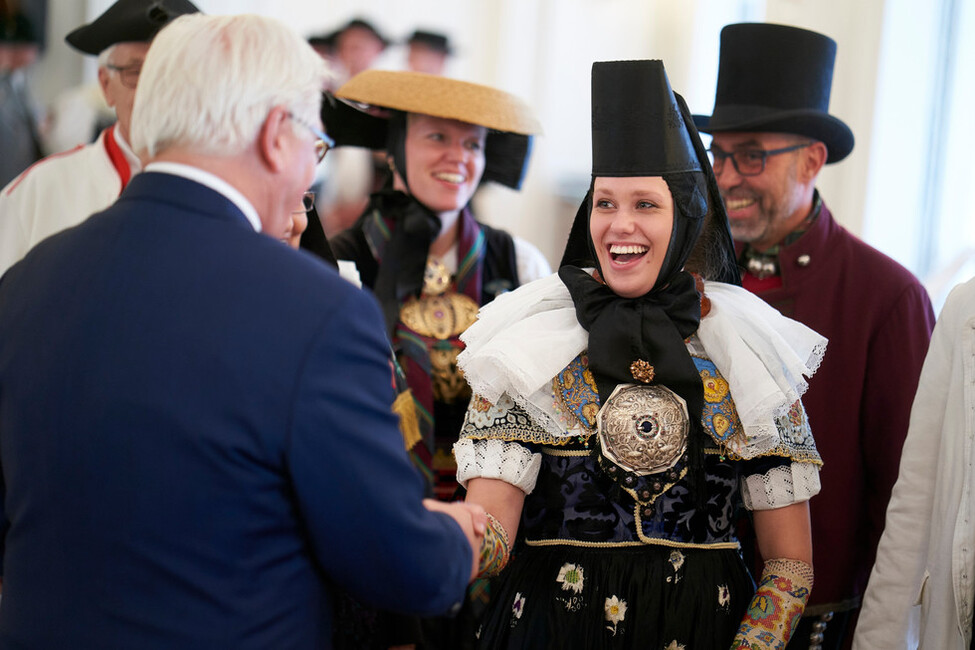 Bundespräsident Frank-Walter Steinmeier bei einer Begegnung mit einem Mitglied einer Gruppe des Deutschen Trachtenverbands e.V. während des Empfangs im Großen Saal von Schloss Bellevue