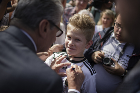 Bundespräsident Joachim Gauck schreibt ein Autogramm für einen Jungen