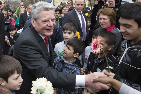 Bundespräsident Joachim Gauck wird von Bewohnern des heutigen Übergangswohnheims begrüßt