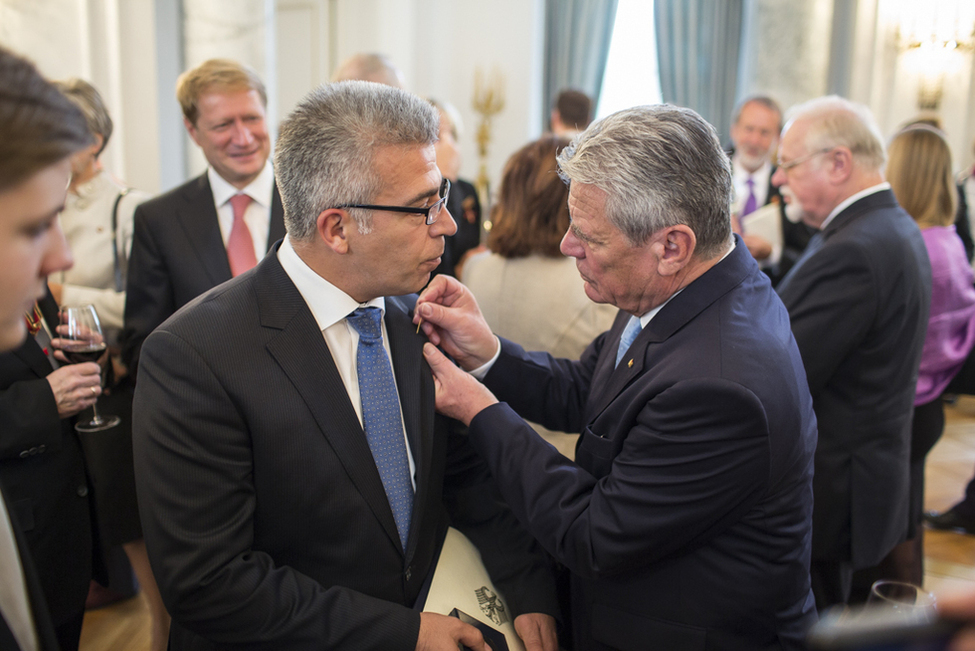 Bundespräsident Joachim Gauck steckt Nejdet Niflioğlu die Miniatur des Verdienstordens beim Empfang an das Revers