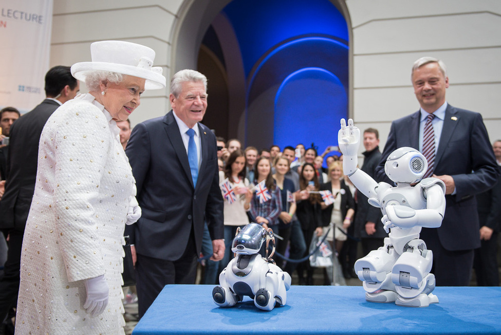 Bundespräsident Joachim Gauck und Königin Elizabeth II bei der Vorstellung eines Studentenprojektes mit einem humanoiden Roboter und einem Roboterhund bei dem Festakt '50 Jahre Queen's Lecture' an der Technischen Universität Berlin 