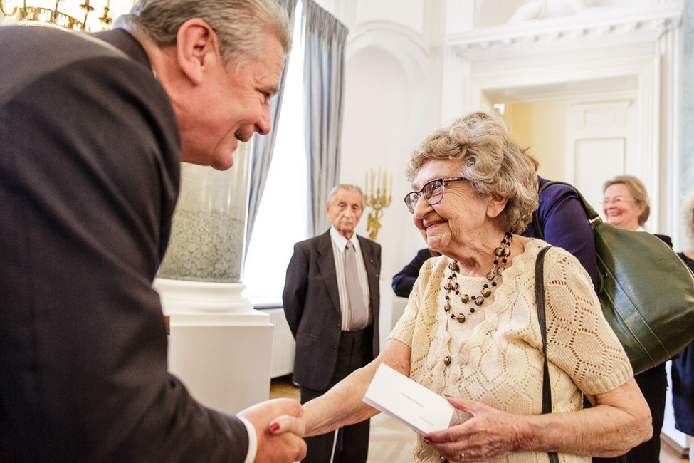 Bundespräsident Joachim Gauck begrüßt die Gäste des Mittagessens für Repräsentanten der Lagergemeinschaften ehemaliger nationalsozialistischer Konzentrationslager im Langhanssaal in Schloss Bellevue