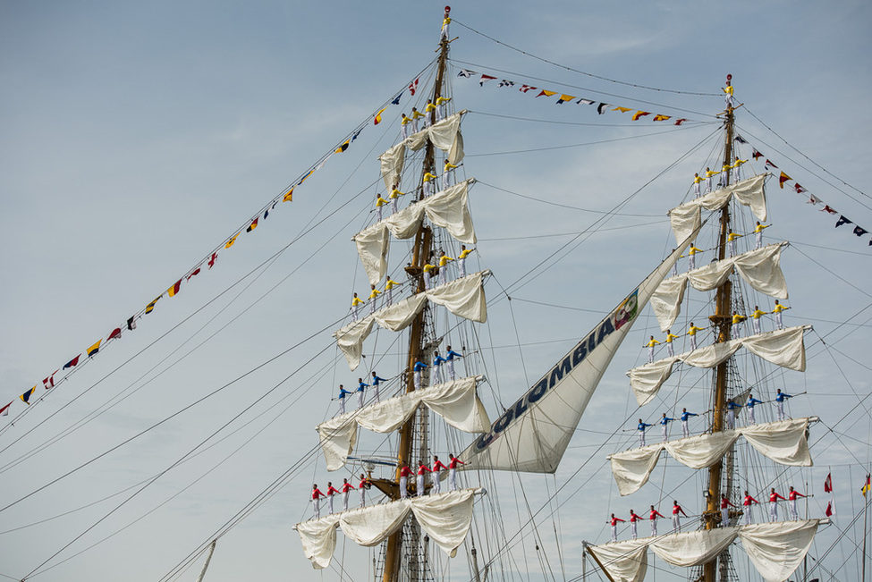 Menschen stehen auf den Mästen eines Windjammers bei der Schiffsparade beim Auftakt der Sail Bremerhaven 2015