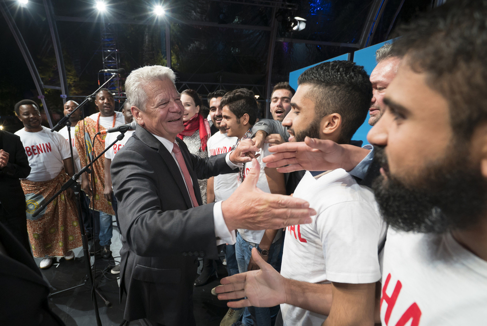 Bundespräsident Joachim Gauck begrüßt Mitglieder des Flüchtlingschors `Zuflucht Kultur e.V.' auf der Bühne im Schlosspark anlässlich des Bürgerfests des Bundespräsidenten 2015 