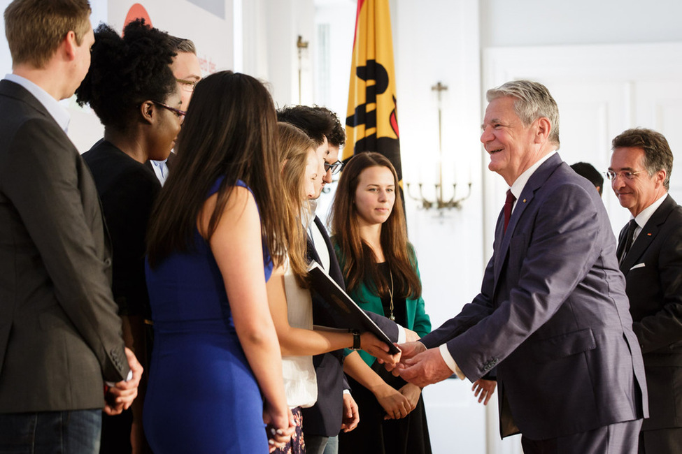 Bundespräsident Joachim Gauck übergibt eine Urkunde an ein Gewinnerteam bei der Preisverleihung des Schulwettbewerbs des Bundespräsidenten zur Entwicklungspolitik im Großen Saal in Schloss Bellevue 