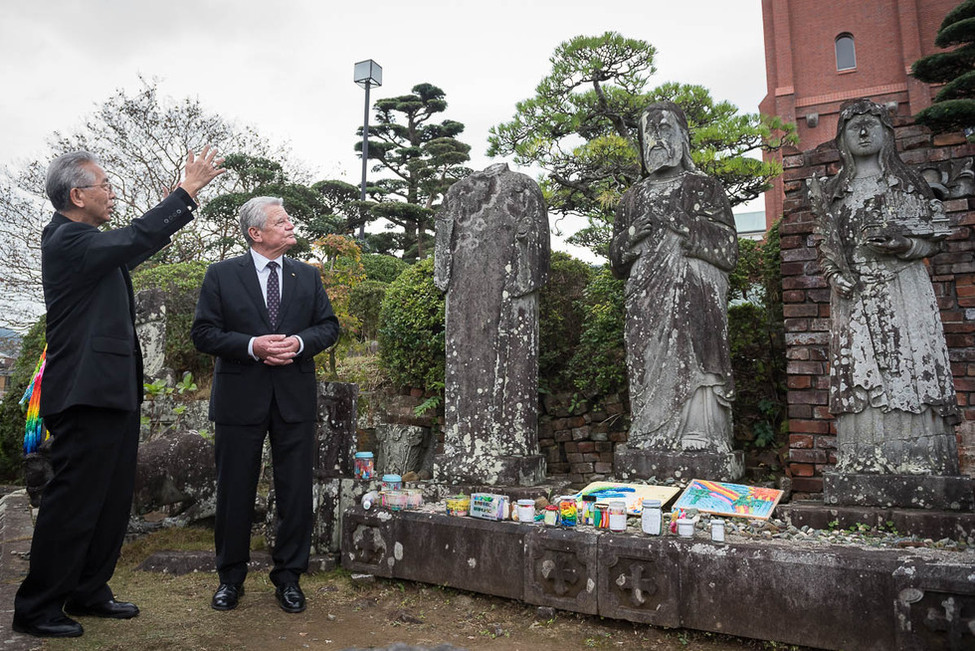 Bundespräsident Joachim Gauck beim Gang mit dem Erzbischof Joseph Takami zu den von der Atombombe beschädigten Statuen der ursprünglichen Kathedrale anlässlich des offiziellen Besuchs in Japan