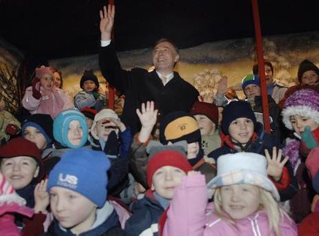 Der Bundespräsident, umringt von Kindern, winkt.