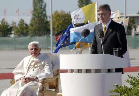 Bundespräsident Horst Köhler steht am Rednderpult; Papst Benedikt XVI. sitzt auf einem Stuhl links daneben. 
