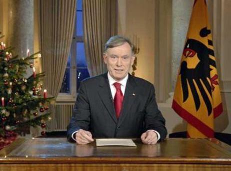 Bundespräsident Horst Köhler sitzt an einem Schreibtisch; links hinter ihm steht ein Weihnachtsbaum, rechts die Standarte.