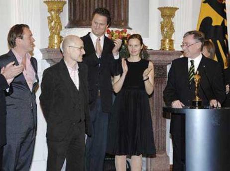 Bundespräsident Horst Köhler steht am Rednerpult; um ihn herum stehen die Gäste und applaudieren mit Blick auf Ulrich Mühe