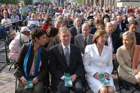 Ehepaar Köhler sitzt in der ersten Reihe einer großen Menschenmenge unter freiem Himmel