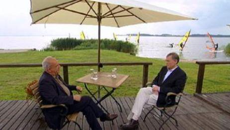 Der Bundespräsident und Peter Hahne sitzen auf einer Holzveranda unter einem Sonnenschirm