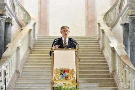 Der Bundespräsident steht an einem Rednerpult im barocken Treppenhaus des Schlosses