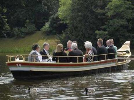 Der Bundespräsident und weitere Personen sitzen in einem Boot und fahren über einen See