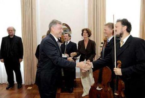 Der Bundespräsident gibt einem Musiker mit Geige die Hand, dahinter stehen weitere Musiker