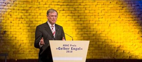 Der Bundespräsident steht an einem Rednerpult. Im Hintergrund ist eine gelb beleuchtete Backsteinwand zu sehen. 