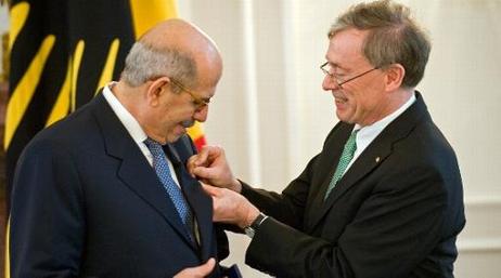 Der Bundespräsident steckt Herrn ElBaradei die Miniatur des Verdienstordens an das Revers des Jackets. Im Hintergrund ist die Standarte des Bundespräsidenten zu sehen. 