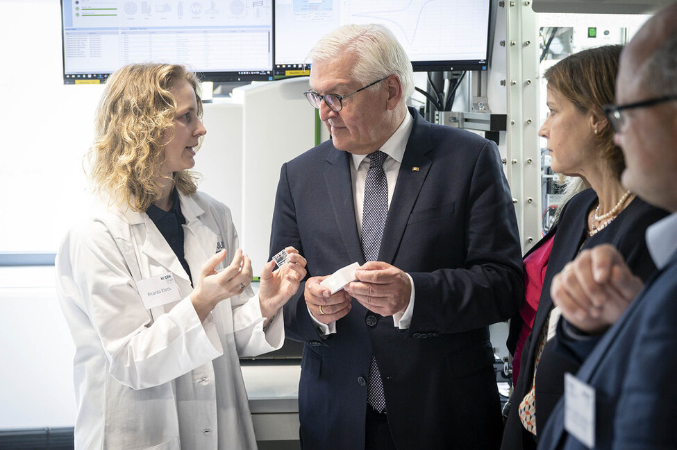 Bundespräsident Frank-Walter Steinmeier im Gespräch mit einer Forscherin zu Wasserstoff während des Rundganges durch das Helmholtz-Institut für Erneuerbare Energien (HI ERN)