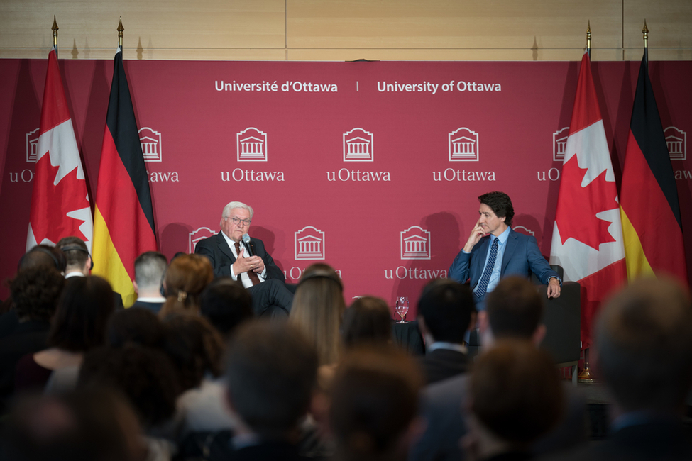 Bundespräsident Steinmeier sitzt mit Premierminister Trudeau auf einem Podium.