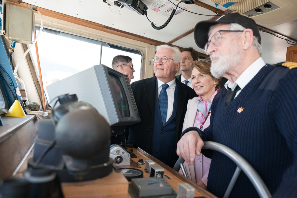 Bundespräsident Steinmeier und Elke Büdenbender gucken dem Kapitän bei einer Hafenrundfahrt über die Schulter und kommen mit ihm ins Gespräch.