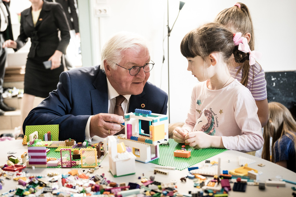 Der Bundespräsident spricht mit einem Mädchen, das mit Legosteinen spielt