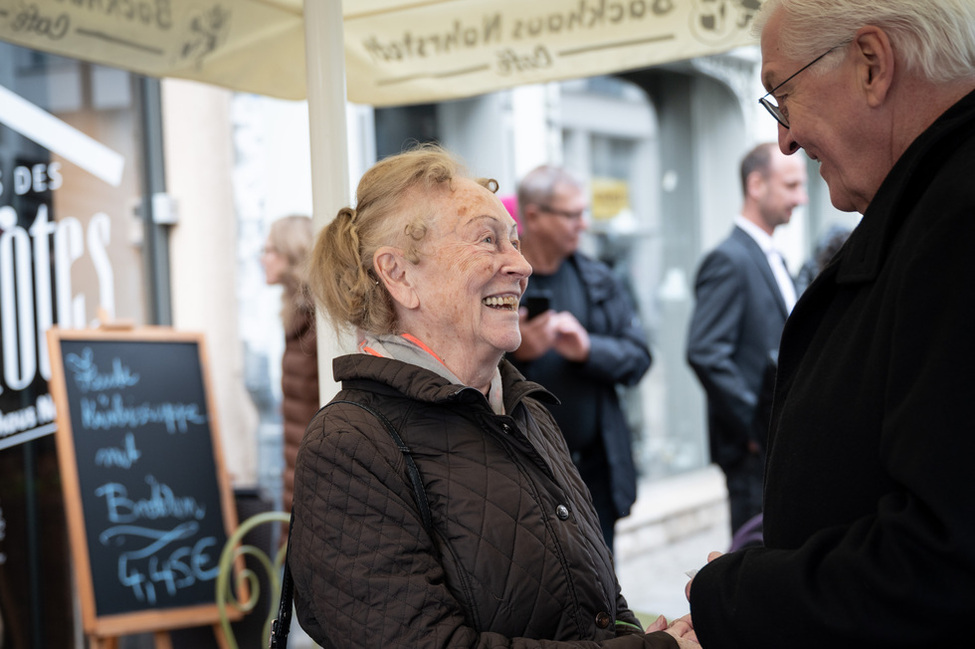 Bundespräsident Frank-Walter Steinmeier im Gespräch mit einer Bürgerin vor einem Café in Meiningen (© Bundesregierung/Sandra Steins) Bundespräsident Frank-Walter Steinmeier im Gespräch mit einer Bürgerin vor einem Café in Meiningen