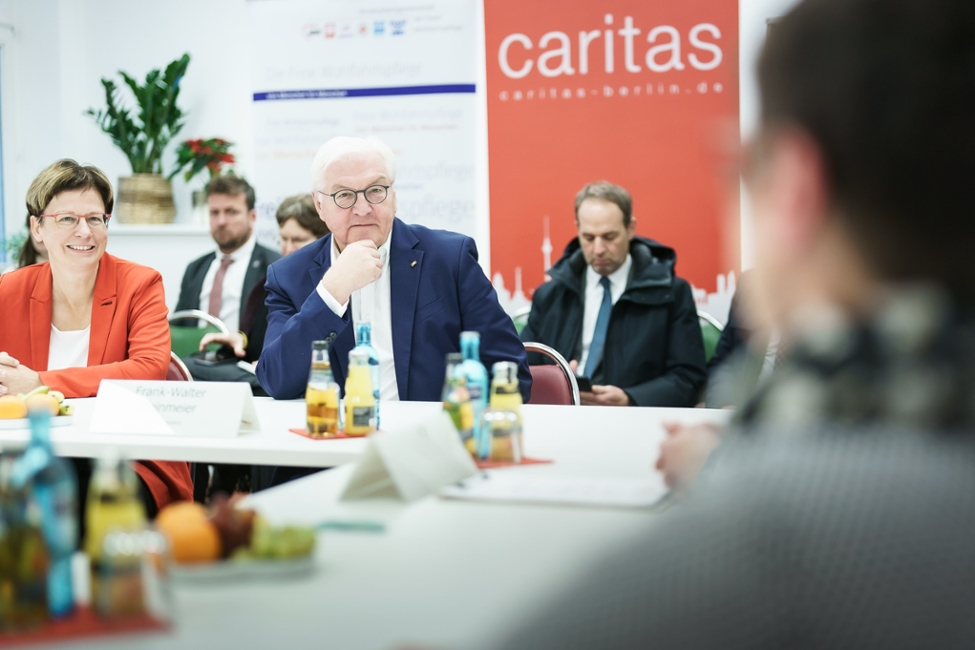 Bundespräsident Steinmeier sitzt mit Helfern der Caritas-Einrichtung an einem Tisch und unterhält sich (© Bundesregierung/Jesco Denzel) Bundespräsident Steinmeier sitzt mit Helfern der Caritas-Einrichtung an einem Tisch und unterhält sich